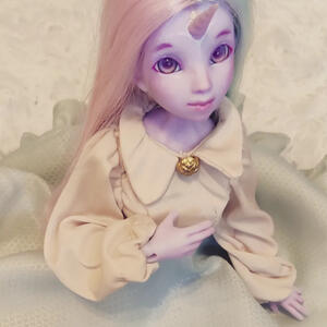 Purple skinned resin doll with a unicorn horn, and flowers in her chest