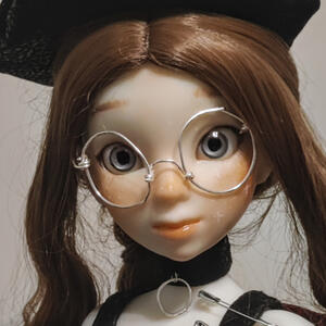 White skinned resin doll with brown hair and glasses